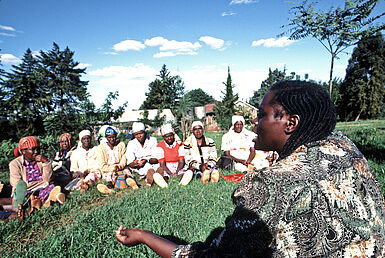 Wangari Maathai sitzt auf einer Wiese mit einer Gruppe von kenianischen Krankenschwestern, um über die Gefahr der massiven Abholzung der kenianischen Wälder zu sprechen.