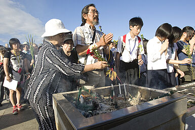 Japanerinnen und Japaner verschiedenen Alters gedenken gemeinsam an die Atombombenopfer. Sie zünden Kerzen an, beten und legen Blumen nieder.