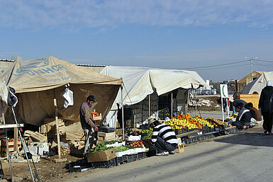 Zelte in Flüchtlingslager, aus denen Obst und Gemüse angeboten wird