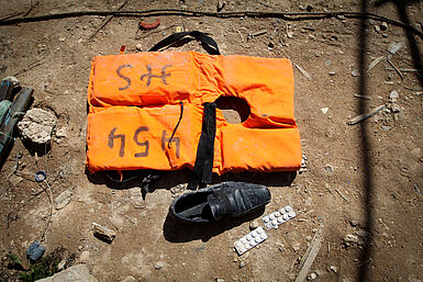 Eine orangefarbene Weste, ein Schuh und Tabletten liegen auf dem Boden.